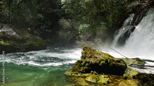 Panning shot of crashing waterfall flowing into Tarawera River during sunny day in paradise of New Zealand photo