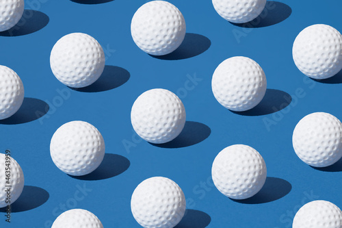 Arranged white golf ball on blue pastel background. Minimal design.