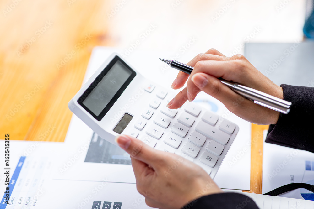 A Businesswoman hand using a calculator with documents financial statistic stock photo,discussion and analysis data the charts and graphs.Market research reports Accounting Finance concept A Businesswoman hand using a calculator with documents financial statistic stock photo,discussion and analysis data the charts and graphs.Market research reports Accounting Finance concept