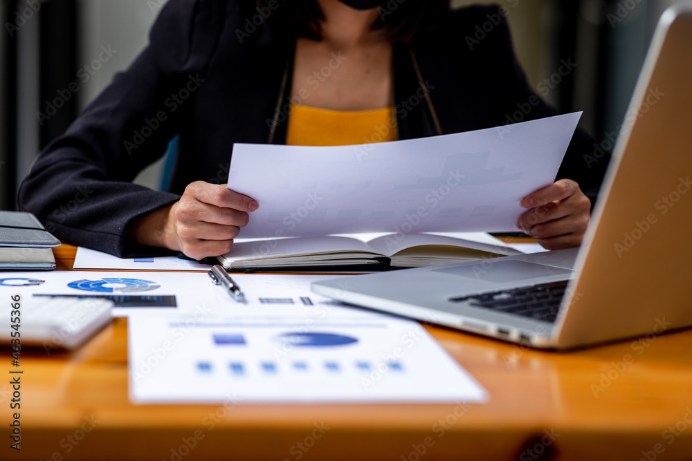 A Businesswoman hand using a calculator with documents financial statistic stock photo,discussion and analysis data the charts and graphs.Market research reports Accounting Finance concept