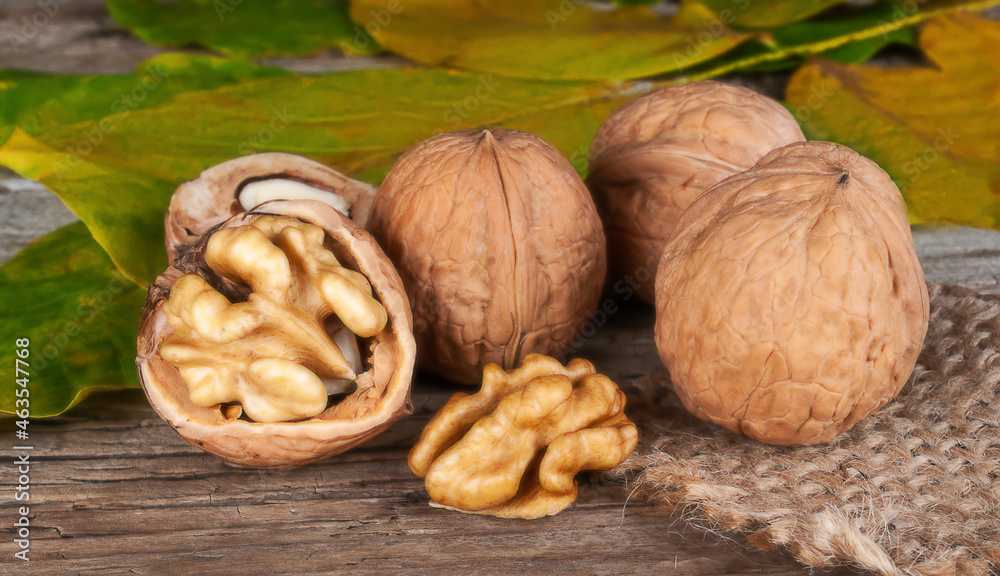 fresh kernels, broken and whole walnuts close-up on wooden background with yellow fall leafs fresh kernels, broken and whole walnuts close-up on wooden background with yellow fall leafs