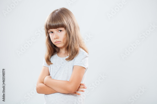 Studio shot portrait of displeased little girl. Copy space on gray background.