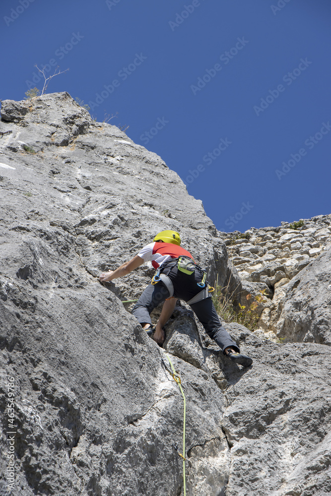 Young man climbing natural high rocky wall Young man climbing natural high rocky wall