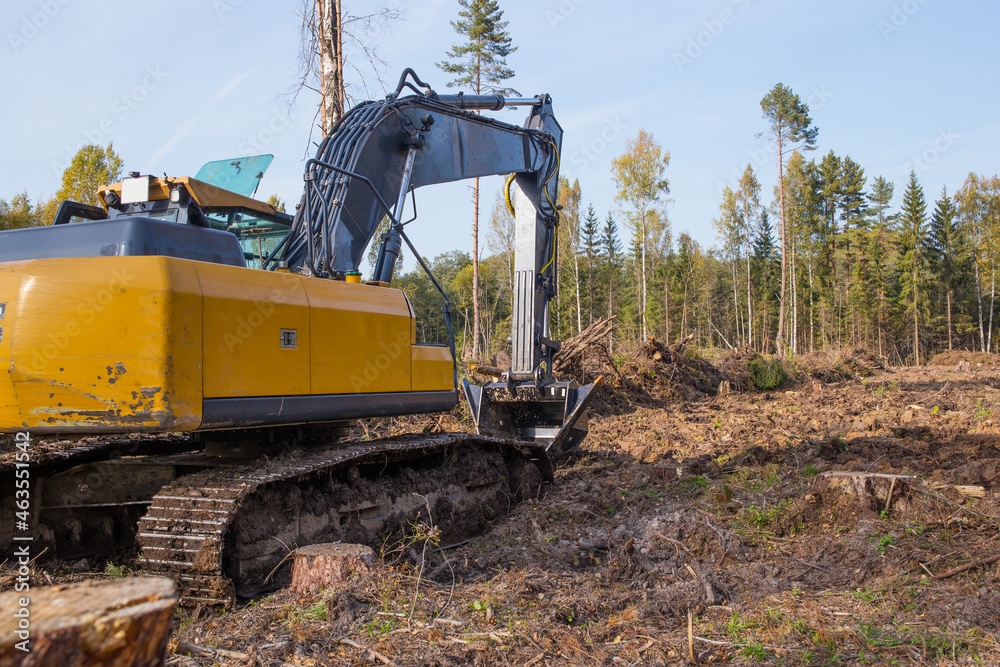 A large excavator works in the forest.