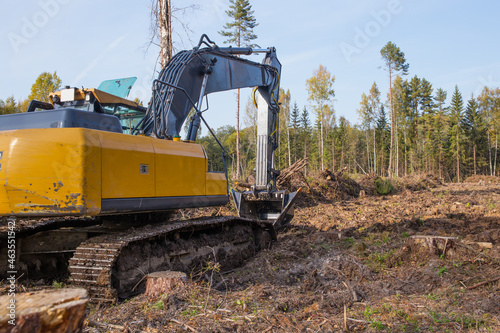 A large excavator works in the forest.