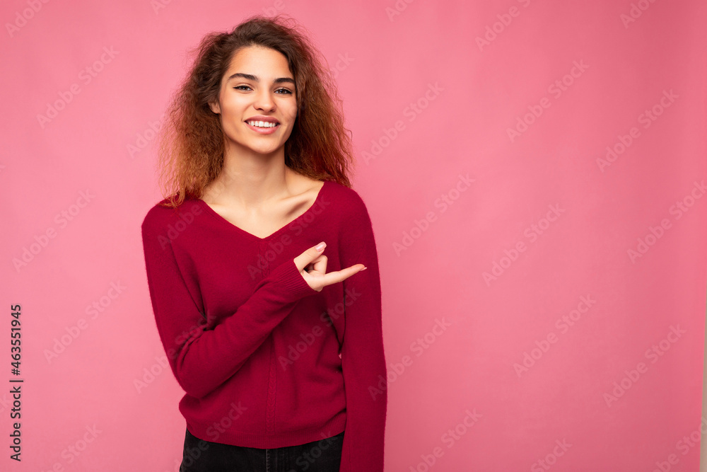 Photo of young happy positive smiling beautiful brunette wavy woman with sincere emotions wearing casual pink jersey isolated over pink background with copy space and pointing at free space for mockup Photo of young happy positive smiling beautiful brunette wavy woman with sincere emotions wearing casual pink jersey isolated over pink background with copy space and pointing at free space for mockup