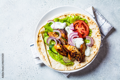 Cooking chicken gyros with vegetables and tzatziki sauce. Greek food concept.