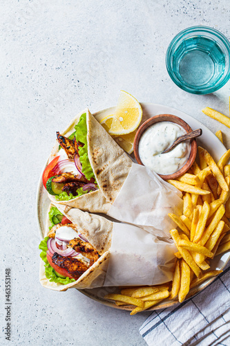 Fotografie Chicken gyros with vegetables, french fries and tzatziki sauce on plate