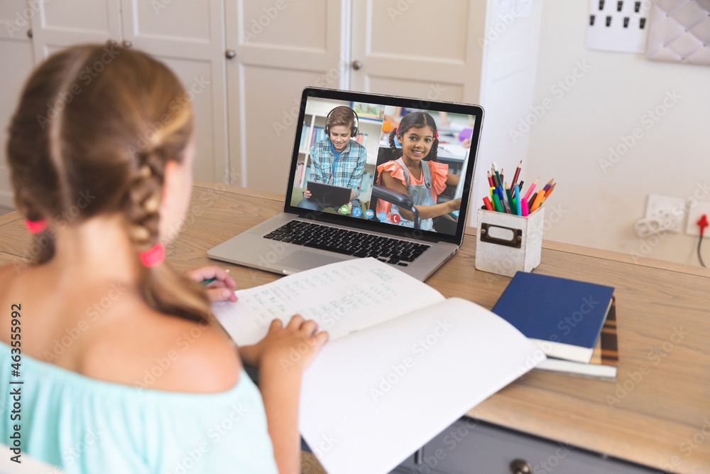 Caucasian girl using laptop for video call, with smiling diverse elementary school pupils on screen Caucasian girl using laptop for video call, with smiling diverse elementary school pupils on screen
