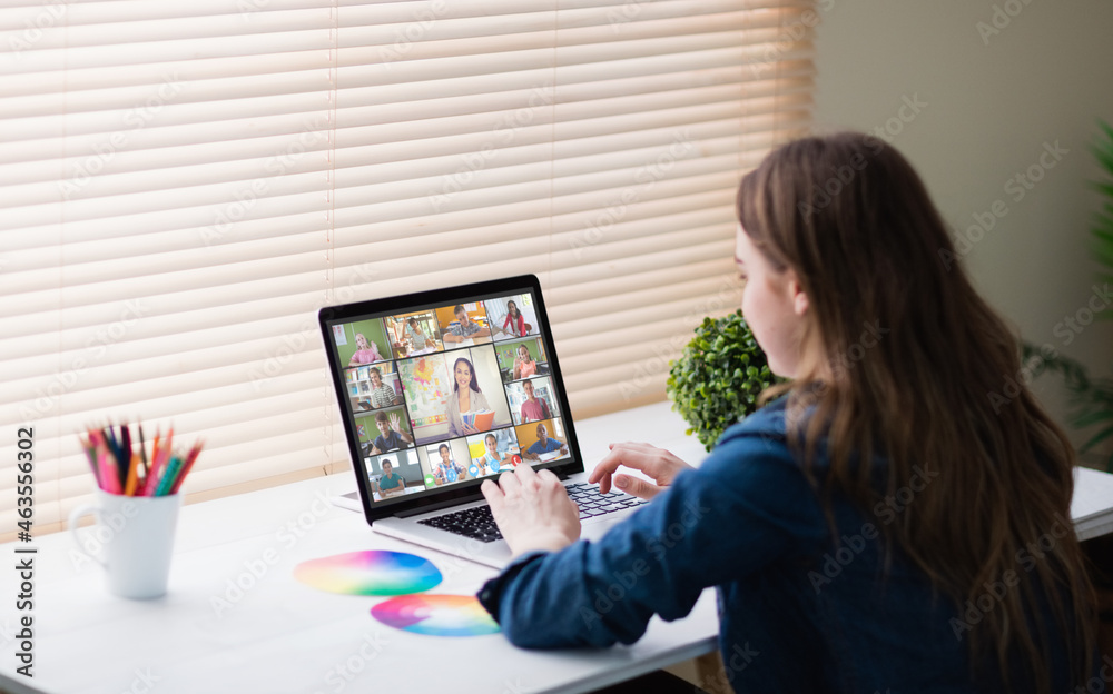 Caucasian girl using laptop for video call, with smiling diverse elementary school pupils on screen Caucasian girl using laptop for video call, with smiling diverse elementary school pupils on screen