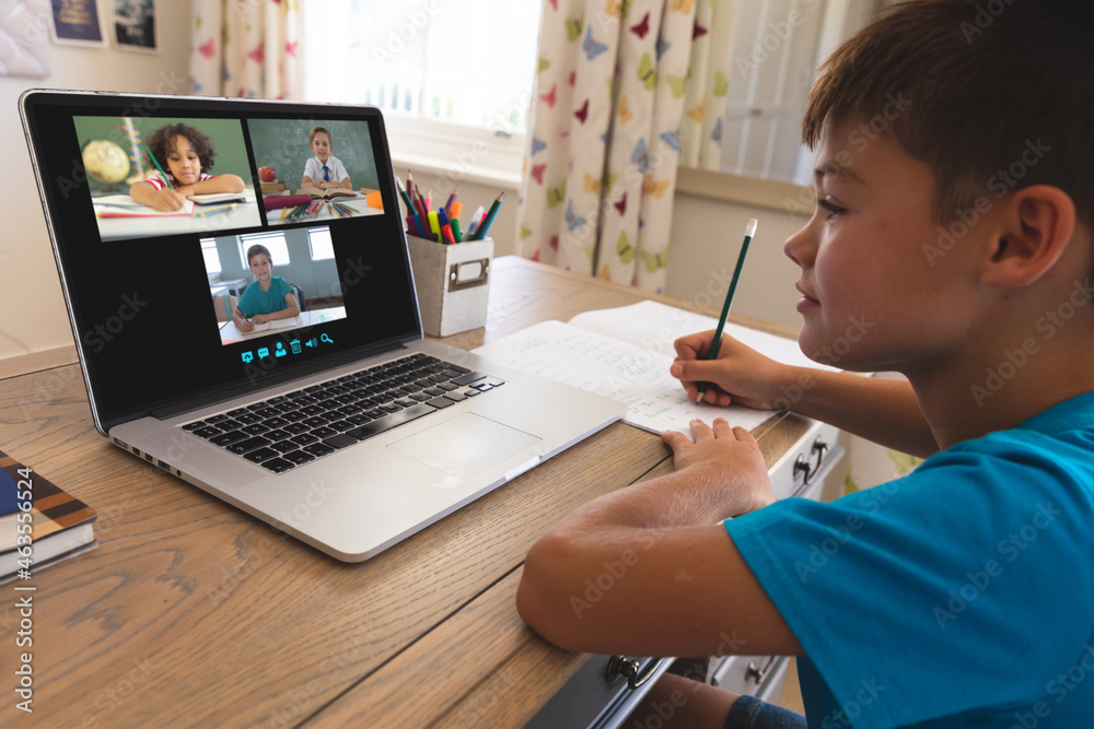 Caucasian boy using laptop for video call, with smiling diverse elementary school pupils on screen Caucasian boy using laptop for video call, with smiling diverse elementary school pupils on screen