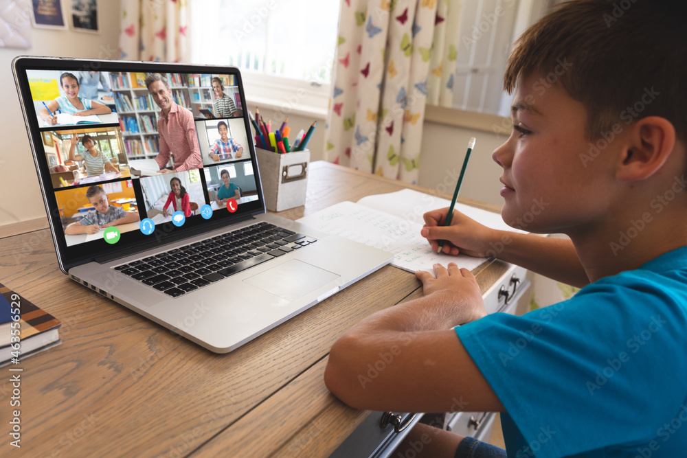 Caucasian boy using laptop for video call, with smiling diverse elementary school pupils on screen Caucasian boy using laptop for video call, with smiling diverse elementary school pupils on screen