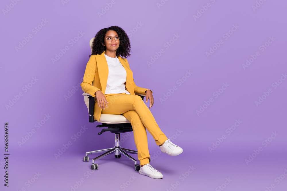Photo of dreamy shiny woman dressed yellow suit spectacles sitting chair empty space isolated violet color background Photo of dreamy shiny woman dressed yellow suit spectacles sitting chair empty space isolated violet color background