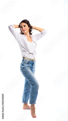 portrait of a woman in the studio on a white, isolated background. White shirt, blue jeans, black hair. beautiful model