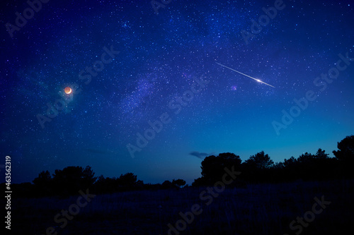 Landscape silhouette of a evening sky with crescent Moon eclipse, meteor, shooting star and planets.