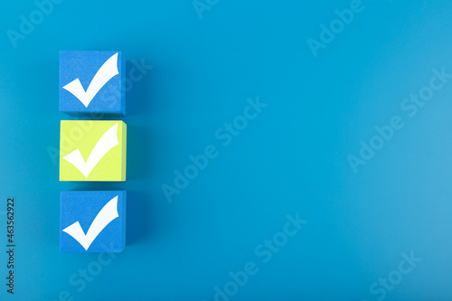 Three checkmarks on blue and yellow cubes against blue background with copy space
