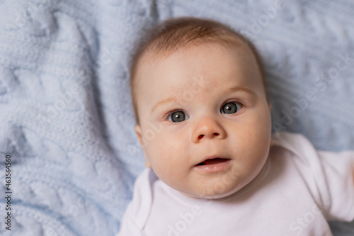 portrait of cute smiling newborn baby lying on his back on blue knitted blanket. breastfeeding. concept of a happy childhood and motherhood. healthy child. High quality photo