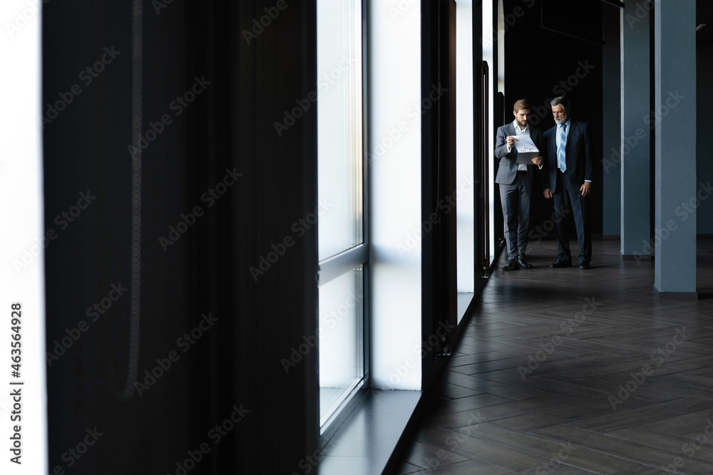 Two colleagues communicating in corridor, partners walking in the modern office Two colleagues communicating in corridor, partners walking in the modern office