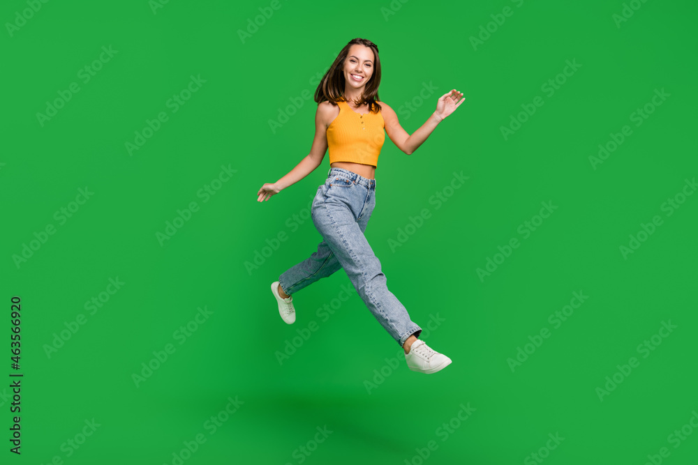 Full size photo of young nice brunette lady run wear top jeans shoes isolated on green background
