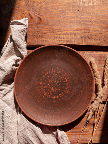 Empty craft handmade clay plate and pampas grass wooden background. Table place hand crafted dish Natural cottagecore styled tableware minimal home interior decor Restaurant food countryside aesthetic