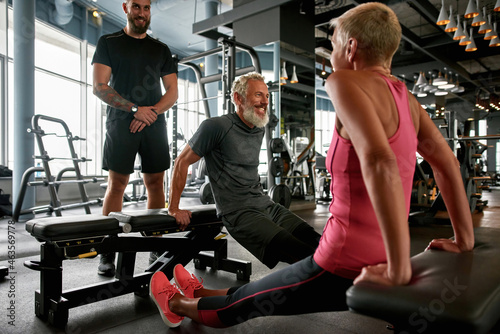 Pair of elderly woman and man working out with trainer