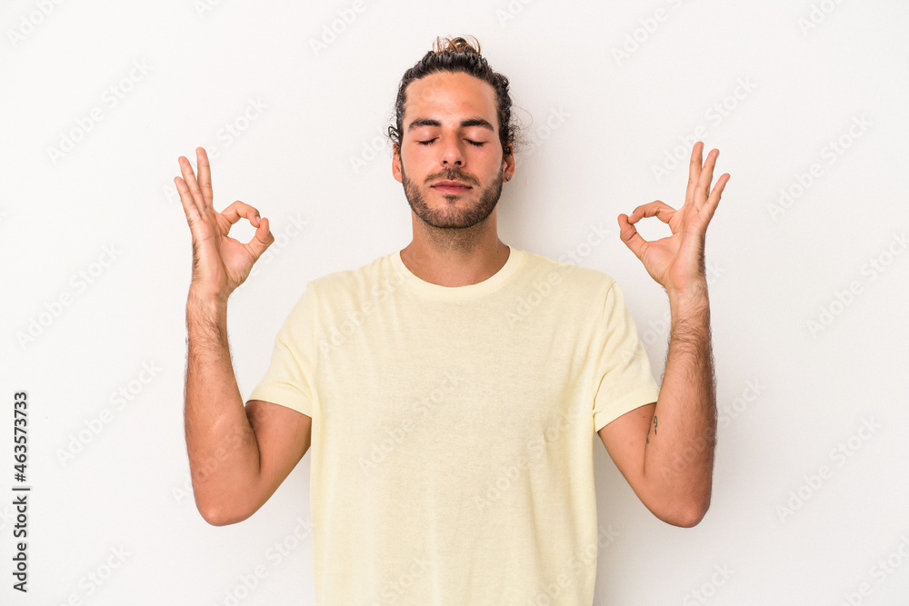 Young caucasian man isolated on white background relaxes after hard working day, she is performing yoga.
