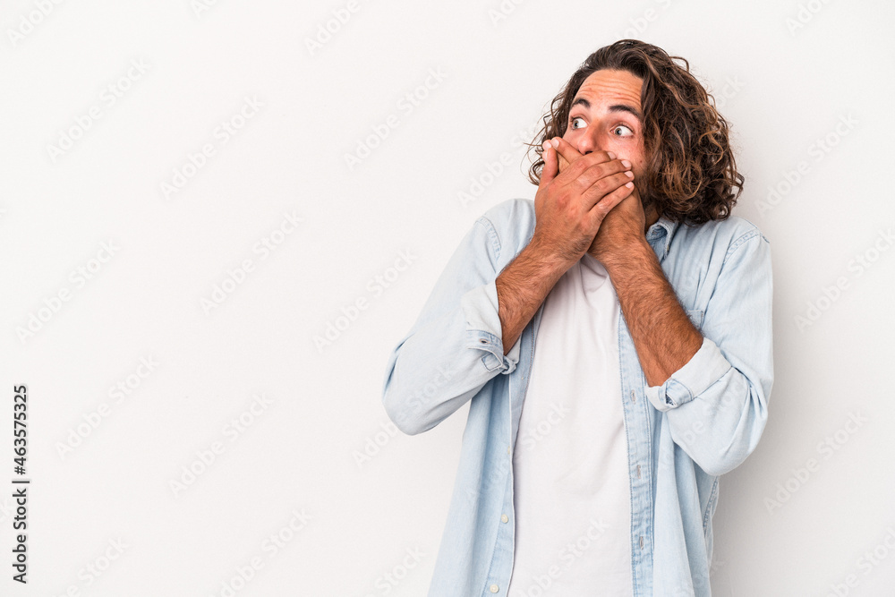 Young caucasian man isolated on white background thoughtful looking to a copy space covering mouth with hand. Young caucasian man isolated on white background thoughtful looking to a copy space covering mouth with hand.