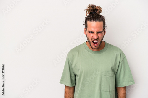Young caucasian man isolated on gray background shouting very angry, rage concept, frustrated.