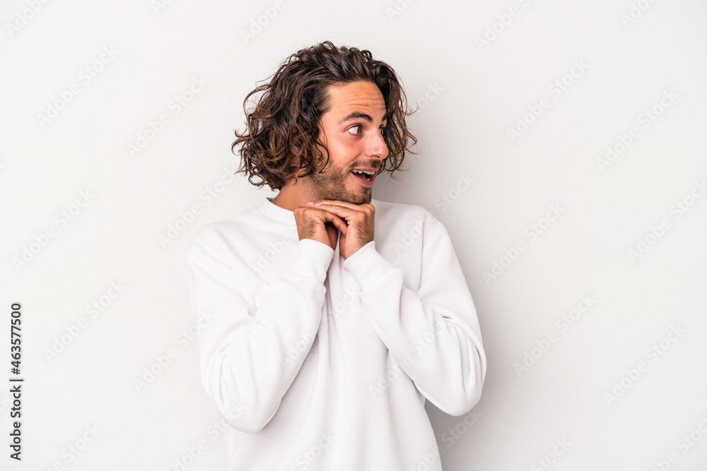 Young caucasian man isolated on gray background praying for luck, amazed and opening mouth looking to front.