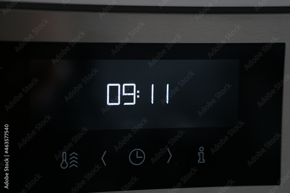 modern digital clock on oven is showing the time 09:11 in white digital numbers on black surface