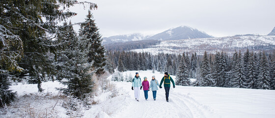Happy family with small daughters walking outdoors in winter nature, Tatra mountains Slovakia.