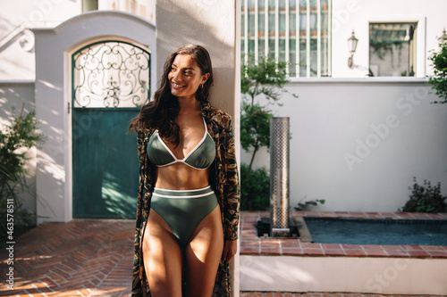 Smiling woman standing outside a hotel in a bikini photo