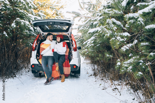 lovely smiling couple sitting in car trunk