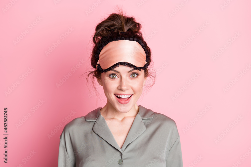 Photo portrait of girl in pajama sleeping mask smiling surprised isolated on pastel pink color background