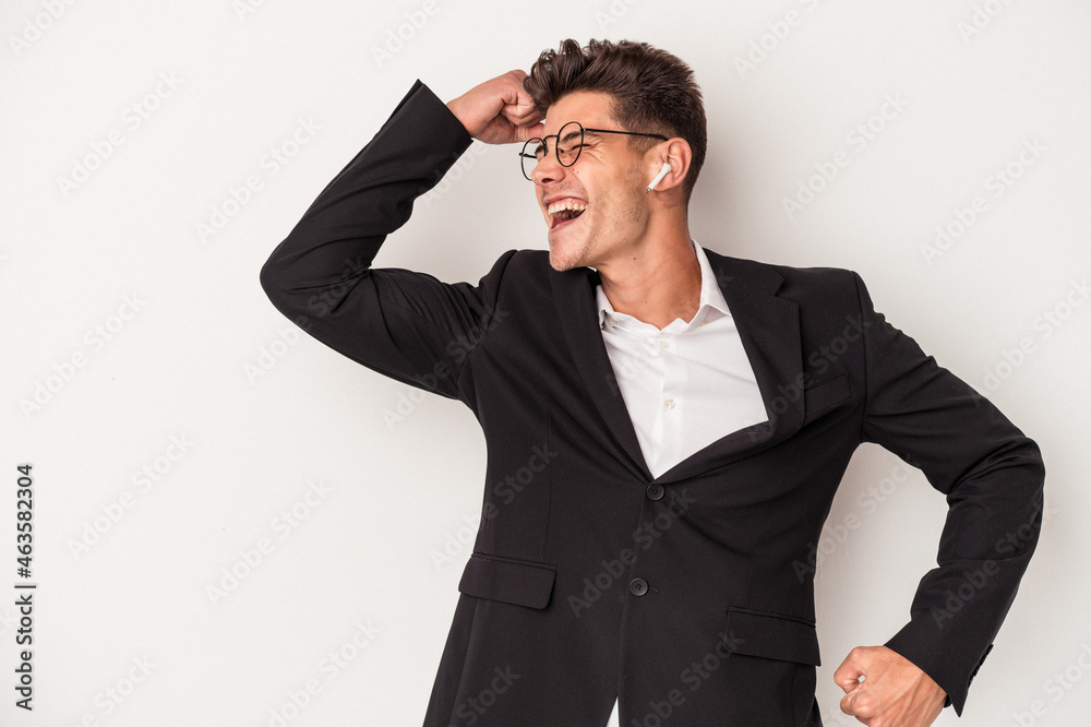 Young business caucasian man wearing headphones isolated on white background raising fist after a victory, winner concept. Young business caucasian man wearing headphones isolated on white background raising fist after a victory, winner concept.