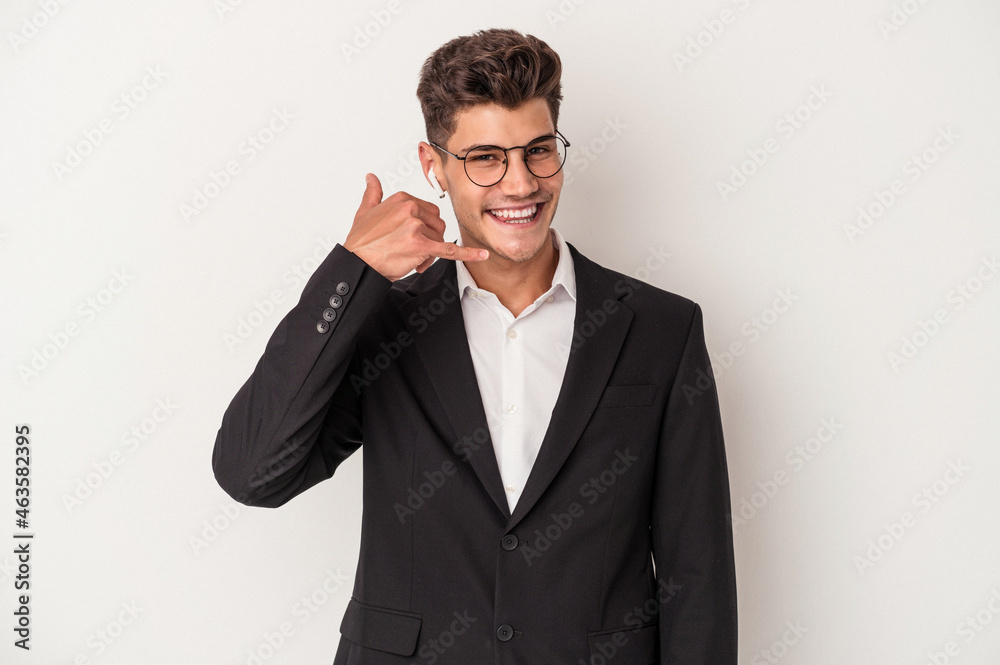 Young business caucasian man wearing headphones isolated on white background showing a mobile phone call gesture with fingers. Young business caucasian man wearing headphones isolated on white background showing a mobile phone call gesture with fingers.