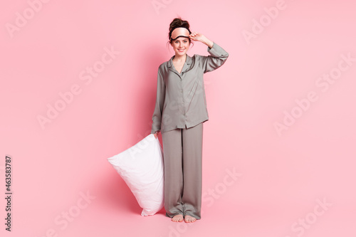 Full body photo of charming cheerful lady arm hold cushion touch sleep mask isolated on pink color background