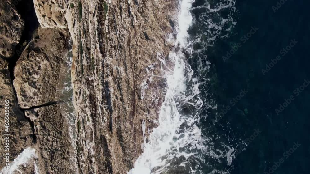 Seawater splashing on rocky coastline with birds flying below, top down view Seawater splashing on rocky coastline with birds flying below, top down view