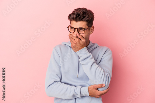 Young caucasian man isolated on pink background laughing happy, carefree, natural emotion.