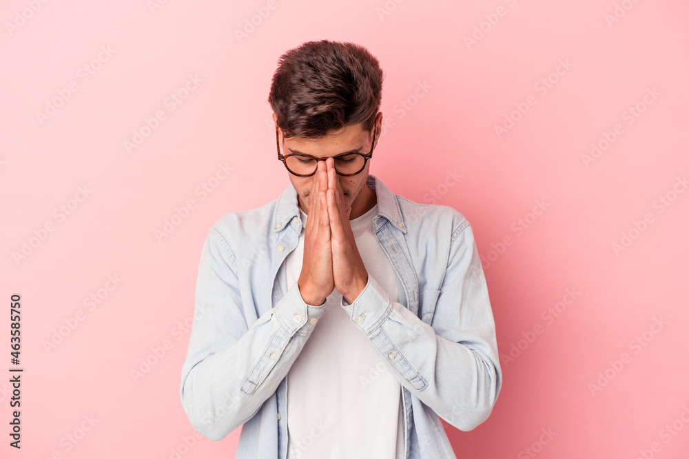 Young caucasian man isolated on pink background praying, showing devotion, religious person looking for divine inspiration. Young caucasian man isolated on pink background praying, showing devotion, religious person looking for divine inspiration.
