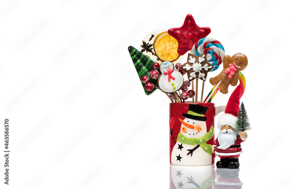 Fototapeta premium Winter concept with New Year decorations and sweets is isolated on a white background. Christmas festive card with Santa Claus, Christmas gingerbread and candy on sticks.