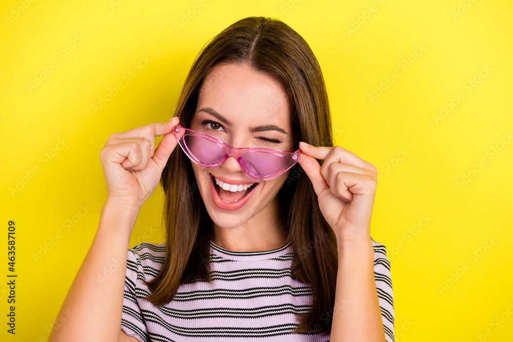 Photo of cute young brunette lady blink wear eyewear white t-shirt isolated on yellow background Photo of cute young brunette lady blink wear eyewear white t-shirt isolated on yellow background