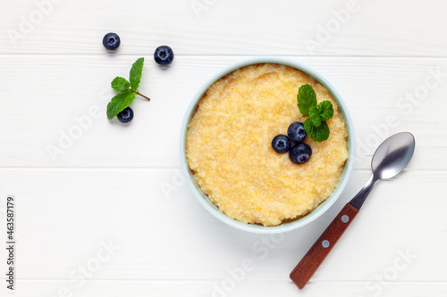 Corn porridge with berries in a bowl on the table. Baby food. Healthy breakfast. Top view