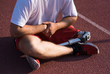 Close up of a Caucasian male with a prosthesis on his leg sitting on the track.