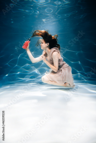 Fitness girl with colorful smoothie. Freshness under water, swims and dives.
