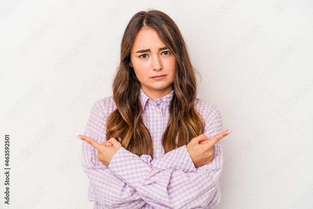 Young caucasian woman isolated on white background points sideways, is trying to choose between two options. Young caucasian woman isolated on white background points sideways, is trying to choose between two options.