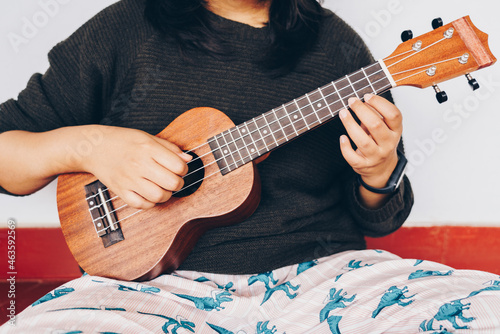 Young woman playing ukulele, close up, cropped