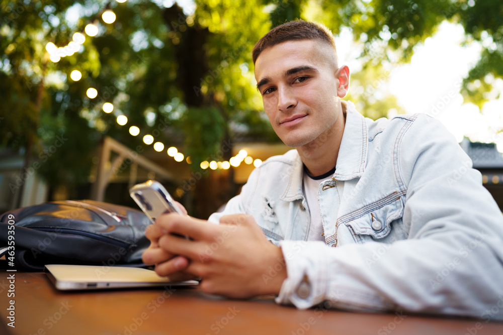 Young man using smartphone while sitting at outdoor cafe Young man using smartphone while sitting at outdoor cafe