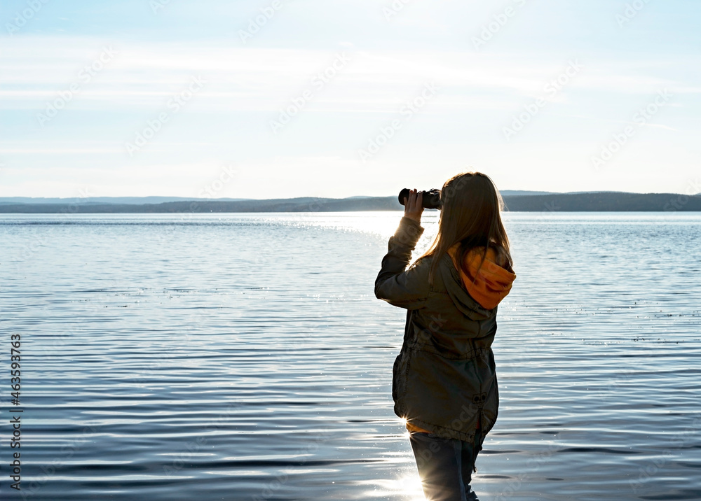 Young woman looking through binoculars at birds on lake Birdwatching, zoology, ecology. Research in nature, observation of animals. Ornithology autumn bird migration Young woman looking through binoculars at birds on lake Birdwatching, zoology, ecology. Research in nature, observation of animals. Ornithology autumn bird migration