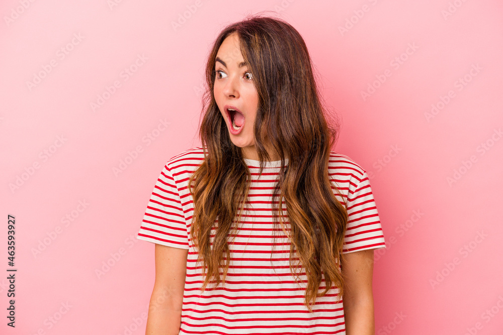 Young caucasian woman isolated on pink background being shocked because of something she has seen.